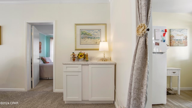 hall with light colored carpet and ornamental molding