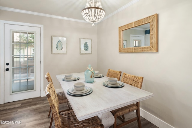 dining space with ornamental molding, wood-type flooring, and an inviting chandelier