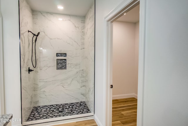 bathroom with wood-type flooring and a tile shower