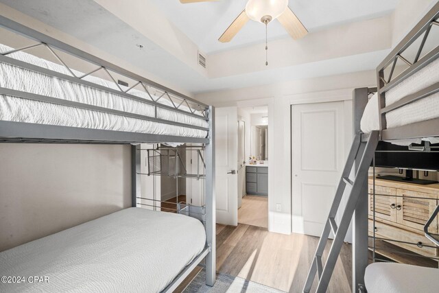 bedroom with connected bathroom, ceiling fan, a closet, and hardwood / wood-style flooring