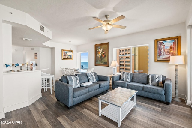 living room with ceiling fan, a textured ceiling, and dark hardwood / wood-style flooring