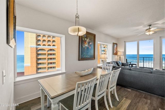 dining room with a water view, ceiling fan, and dark hardwood / wood-style flooring