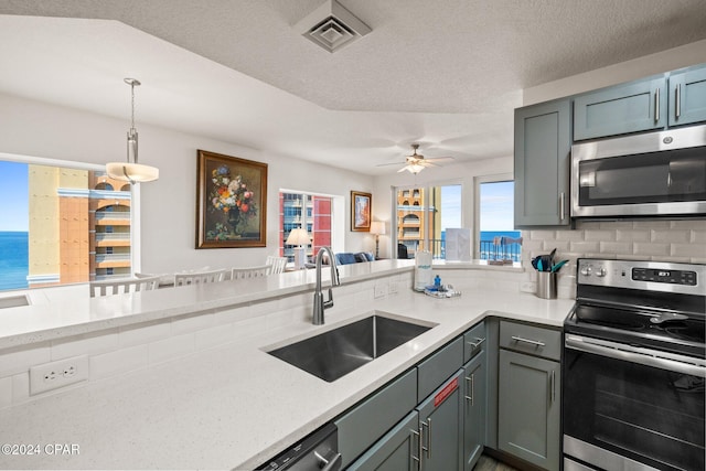 kitchen featuring sink, decorative backsplash, stainless steel appliances, decorative light fixtures, and ceiling fan