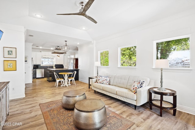 living room with ornamental molding, ceiling fan with notable chandelier, sink, light hardwood / wood-style flooring, and lofted ceiling