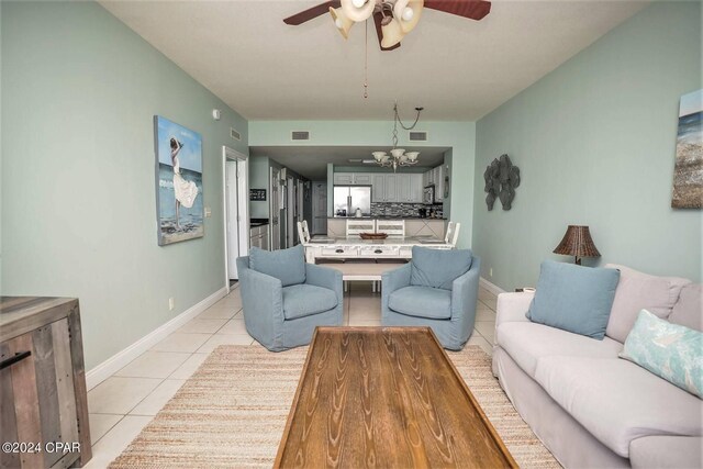 tiled living room with ceiling fan with notable chandelier