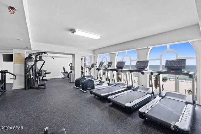 gym with a water view and a textured ceiling