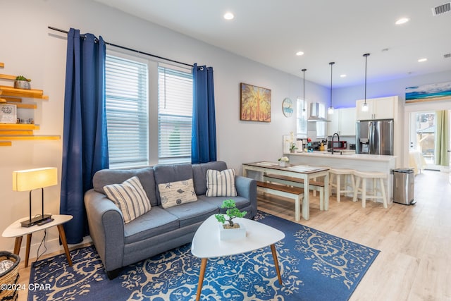 living room with a healthy amount of sunlight, light wood-type flooring, and sink