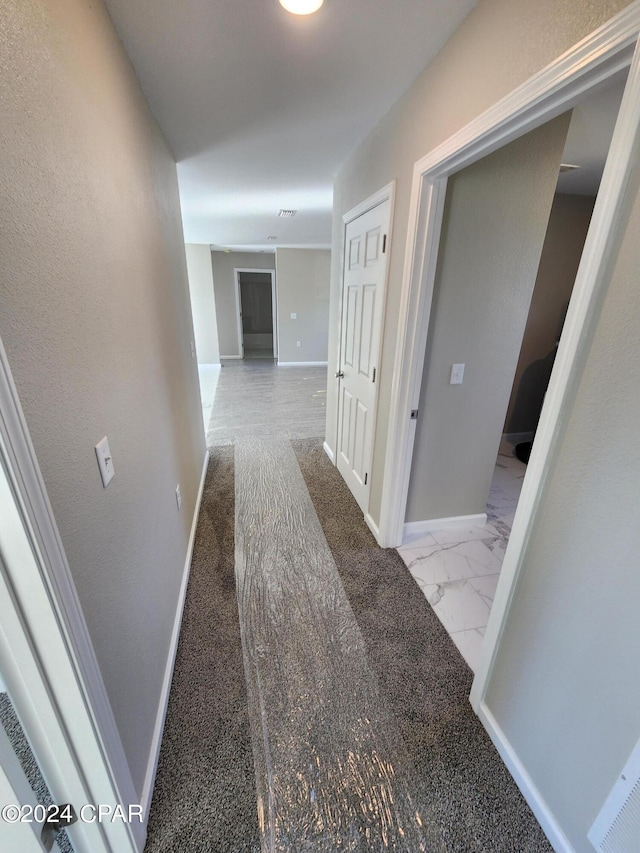 hallway featuring marble finish floor and baseboards