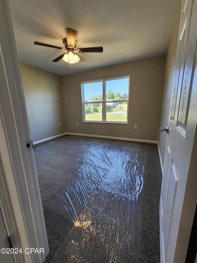 carpeted empty room with ceiling fan and baseboards