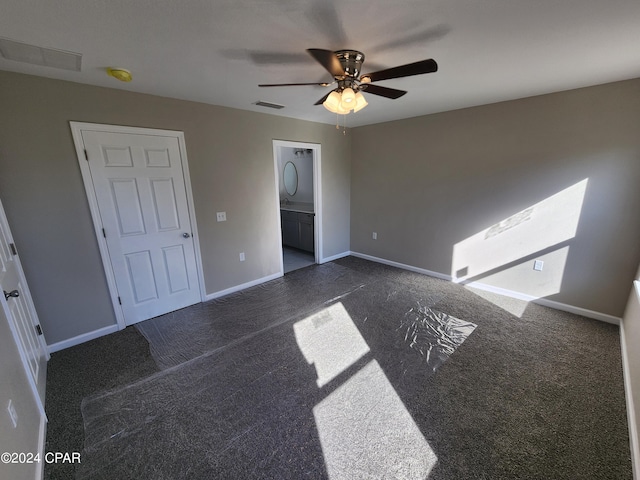 unfurnished bedroom with visible vents, baseboards, dark carpet, and a ceiling fan