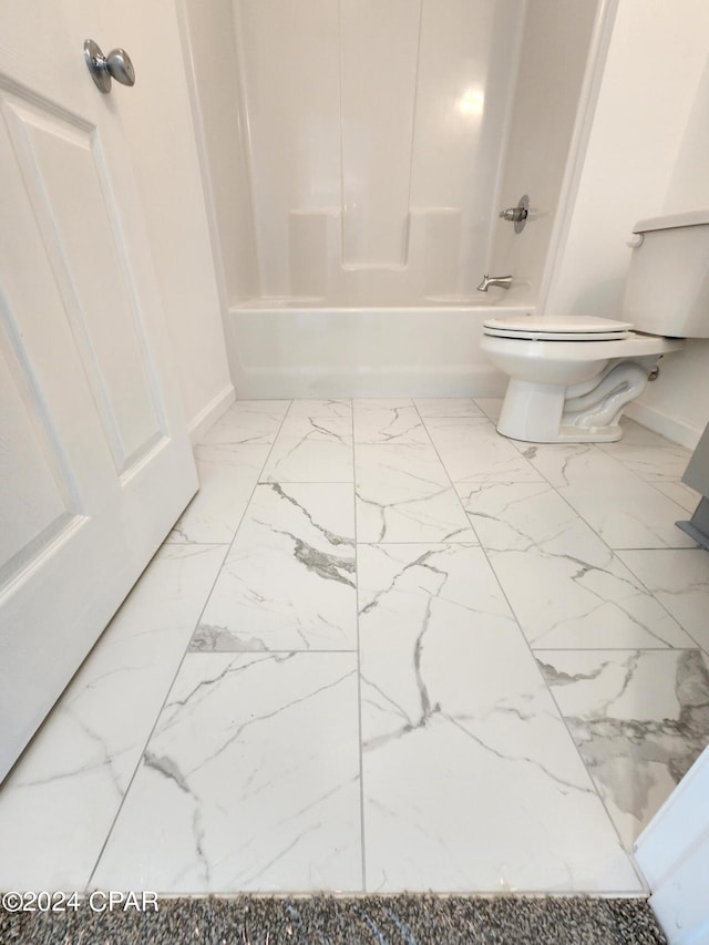 bathroom featuring marble finish floor, shower / washtub combination, toilet, and baseboards