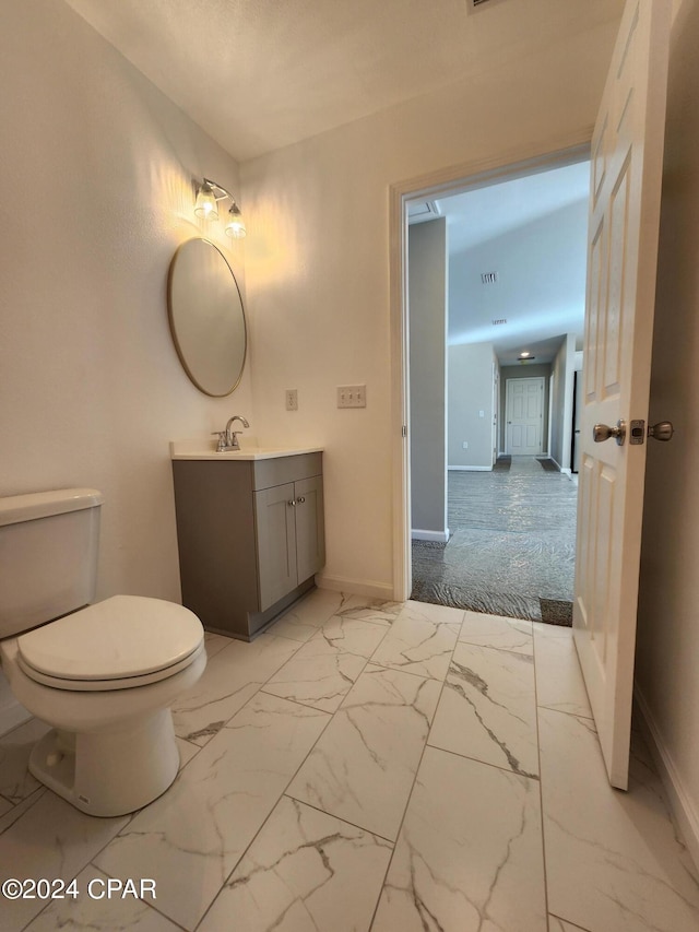 half bath featuring marble finish floor, vanity, and toilet