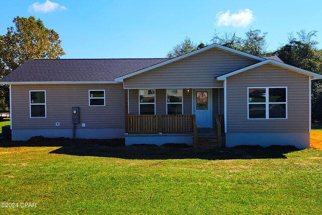 view of front of house featuring covered porch, a shingled roof, and a front yard