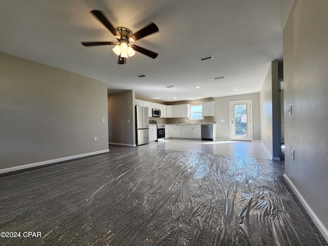 unfurnished living room featuring a ceiling fan, visible vents, and baseboards