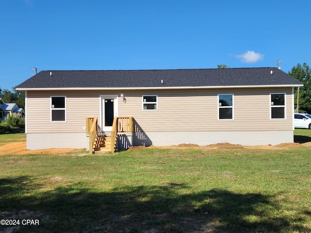 rear view of house with a shingled roof and a yard