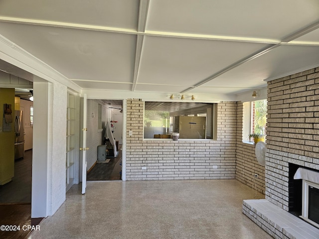 unfurnished living room featuring a brick fireplace and brick wall