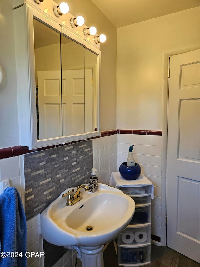 bathroom with hardwood / wood-style flooring, tile walls, and sink