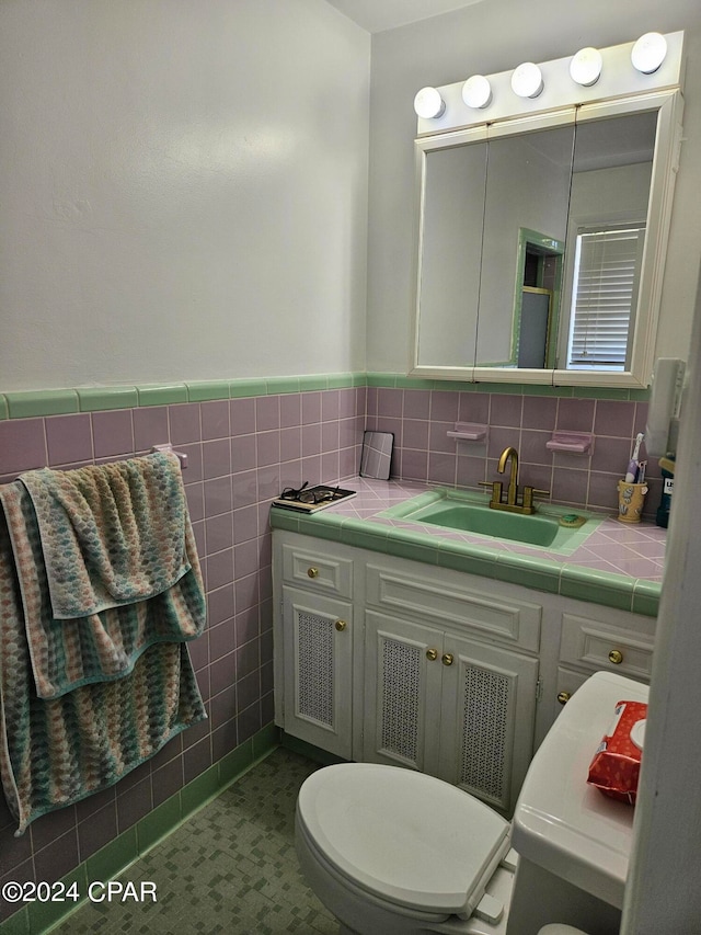 bathroom featuring vanity, toilet, and tile walls