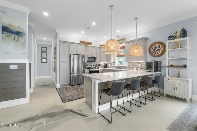 kitchen with a breakfast bar area, kitchen peninsula, ornamental molding, decorative light fixtures, and appliances with stainless steel finishes