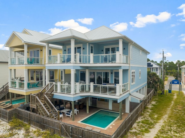 back of property featuring a patio, a fenced in pool, and a balcony