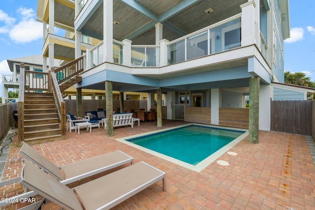 back of property with a patio area, a fenced in pool, and an outdoor living space