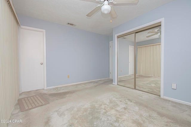 unfurnished bedroom featuring a textured ceiling, light colored carpet, a closet, and ceiling fan