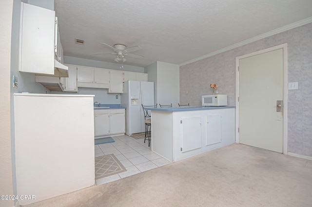 kitchen featuring light carpet, a textured ceiling, white cabinetry, sink, and white appliances