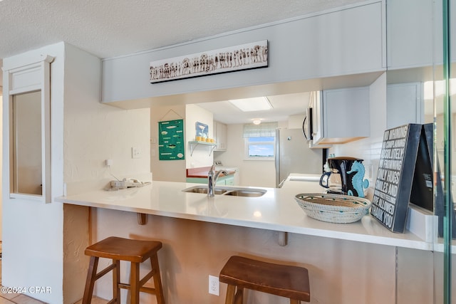 4425 Thomas Dr Unit 707, Panama City, FL 32408 - kitchen featuring a sink, stainless steel microwave, a kitchen bar, a peninsula, and a textured ceiling
