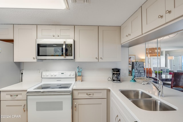 kitchen with a textured ceiling, white cabinetry, sink, and white appliances