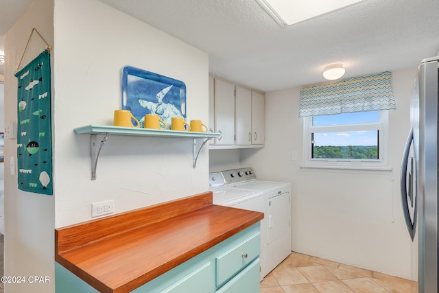 laundry area featuring cabinets, separate washer and dryer, a textured ceiling, and light tile patterned floors