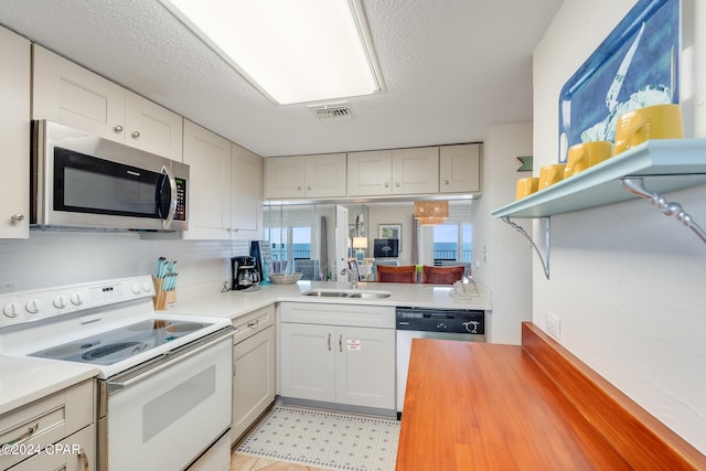 kitchen with sink, white electric range, a textured ceiling, dishwashing machine, and white cabinets