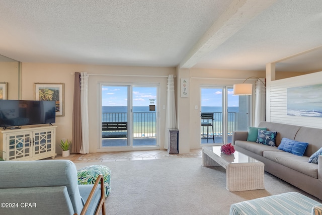 living room featuring plenty of natural light, beam ceiling, a water view, and a textured ceiling