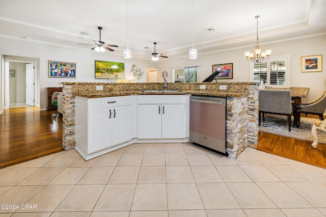 kitchen featuring dishwasher, white cabinets, hanging light fixtures, light hardwood / wood-style flooring, and dark stone countertops