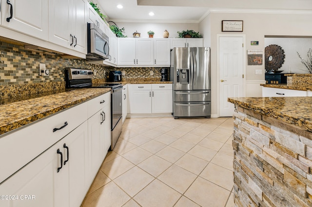 kitchen with stainless steel appliances, dark stone countertops, white cabinets, and backsplash