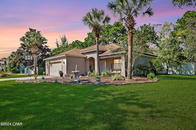 mediterranean / spanish home featuring a garage and a yard