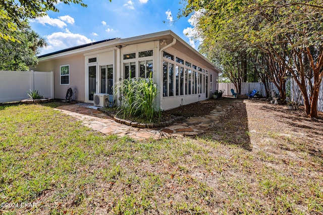 rear view of property with ac unit, a lawn, and a sunroom