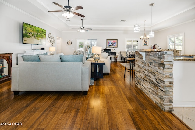 living room featuring crown molding, ceiling fan with notable chandelier, dark hardwood / wood-style flooring, and a raised ceiling