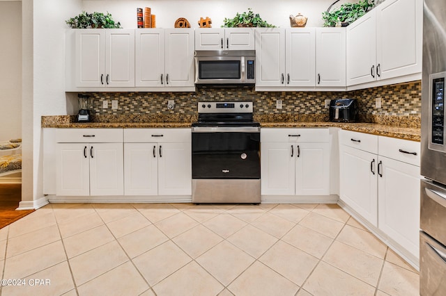 kitchen with dark stone countertops, white cabinetry, appliances with stainless steel finishes, and backsplash