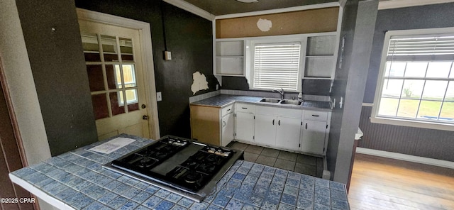 kitchen with a wealth of natural light, white cabinetry, tile counters, and sink