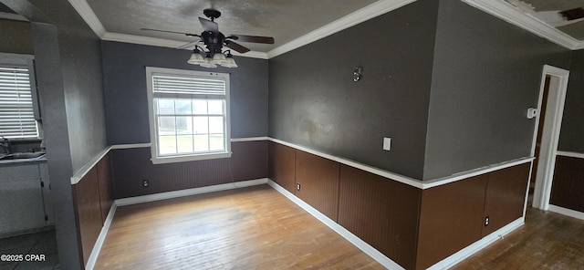 spare room featuring ornamental molding, ceiling fan, sink, hardwood / wood-style flooring, and wood walls