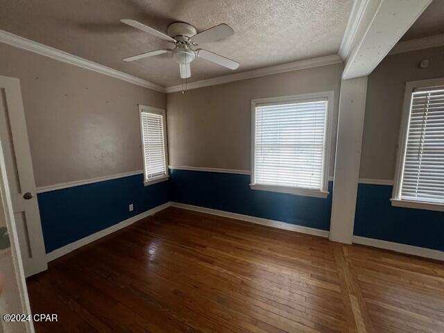 empty room featuring ceiling fan, crown molding, dark wood-type flooring, and a textured ceiling