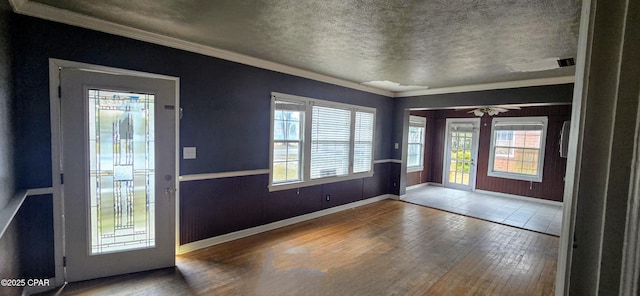 foyer with a textured ceiling, wood-type flooring, and crown molding