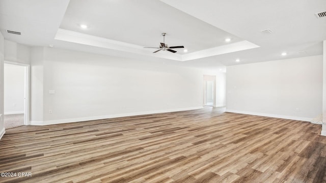 empty room with a tray ceiling, visible vents, and light wood finished floors