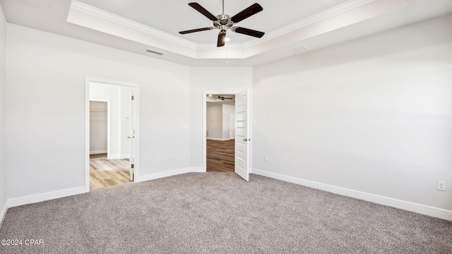 unfurnished bedroom featuring visible vents, baseboards, carpet, crown molding, and a raised ceiling