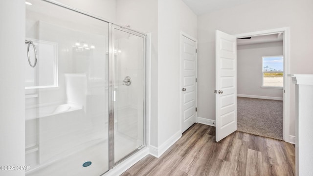 full bath with a shower stall, baseboards, and wood finished floors