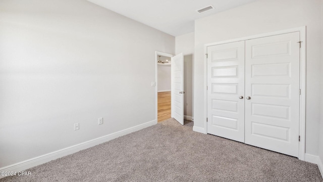 unfurnished bedroom featuring a closet, baseboards, visible vents, and carpet floors