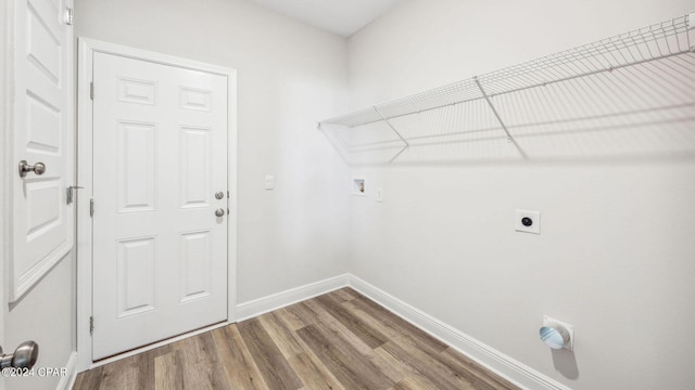 clothes washing area with laundry area, wood finished floors, baseboards, and hookup for an electric dryer