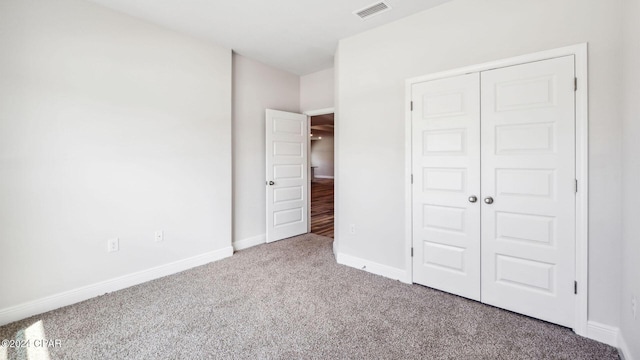 unfurnished bedroom with a closet, visible vents, baseboards, and carpet floors