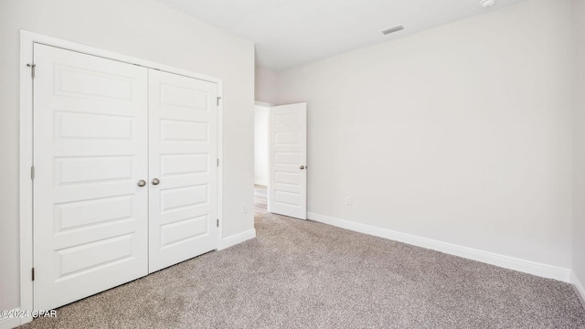 unfurnished bedroom featuring visible vents, baseboards, carpet, and a closet