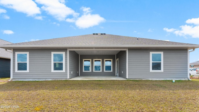 rear view of property with a patio, a yard, and roof with shingles